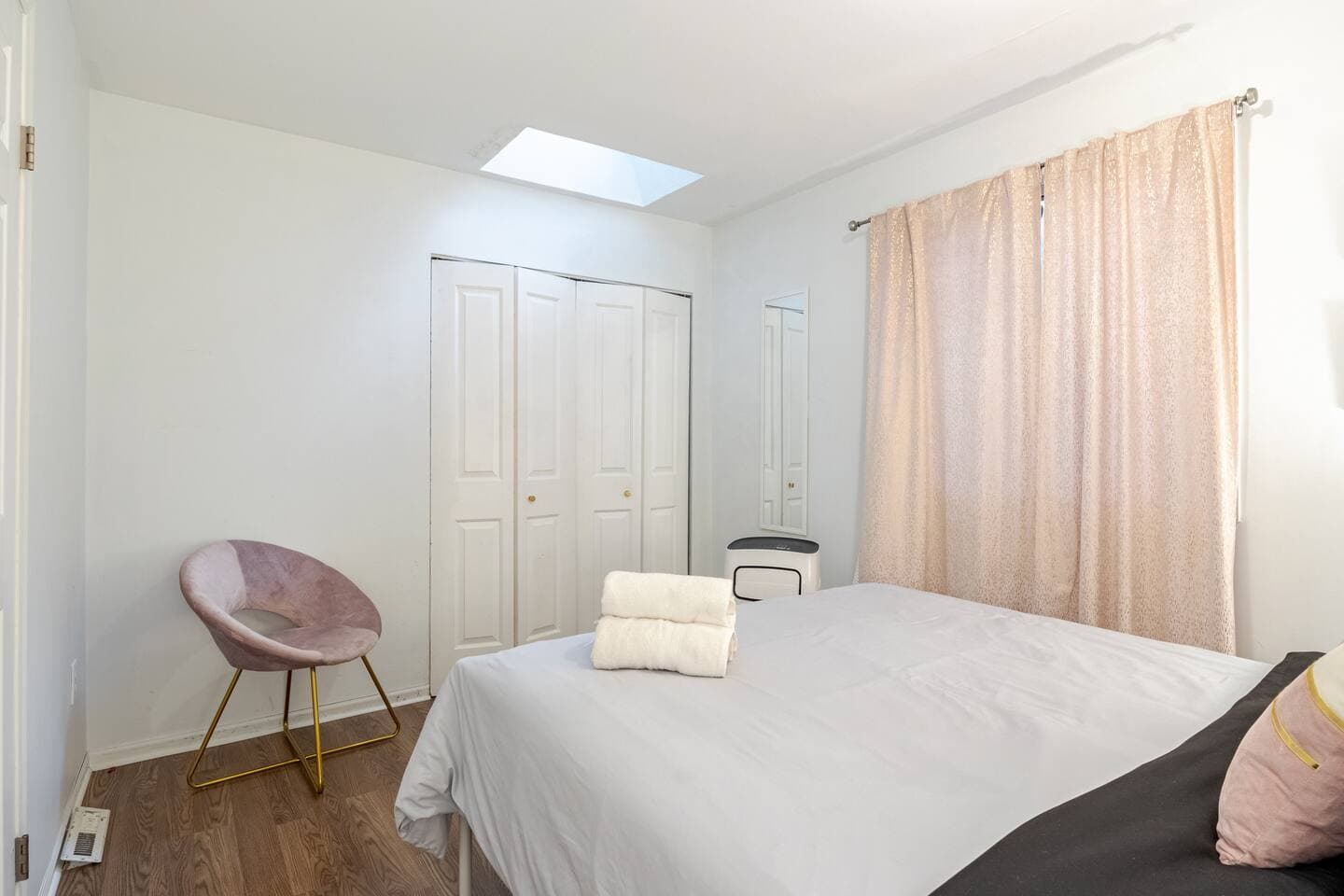 Bedroom 1 — pink accent chair beneath a skylight